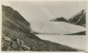 Image of Brother John's glacier Rocks on left a brown glacier and ice on lake a cold blue